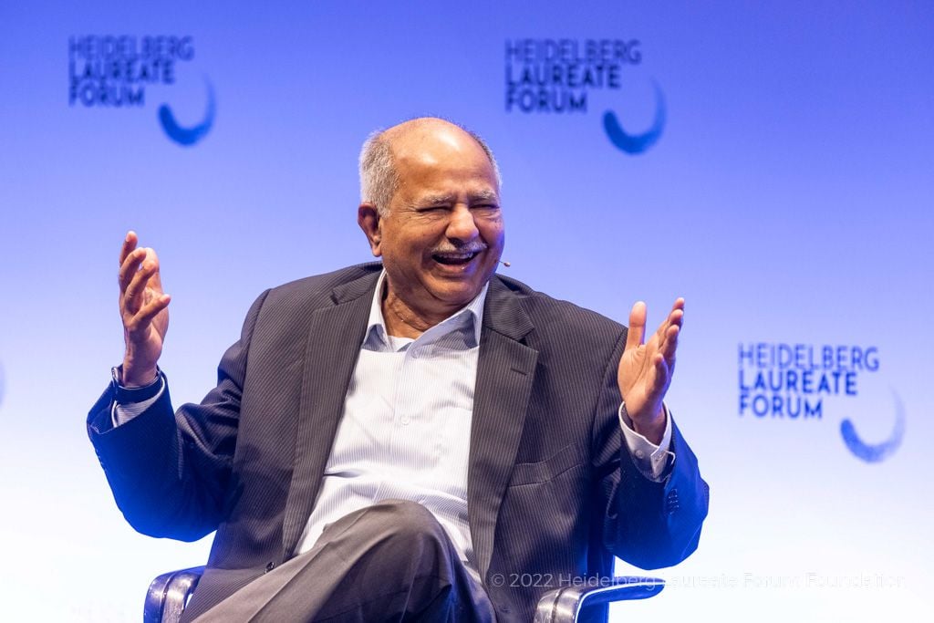 Raj Reddy, a brown-skinned older man with a fringe of white hair around his head, wearing a jacket and shirt but no tie.